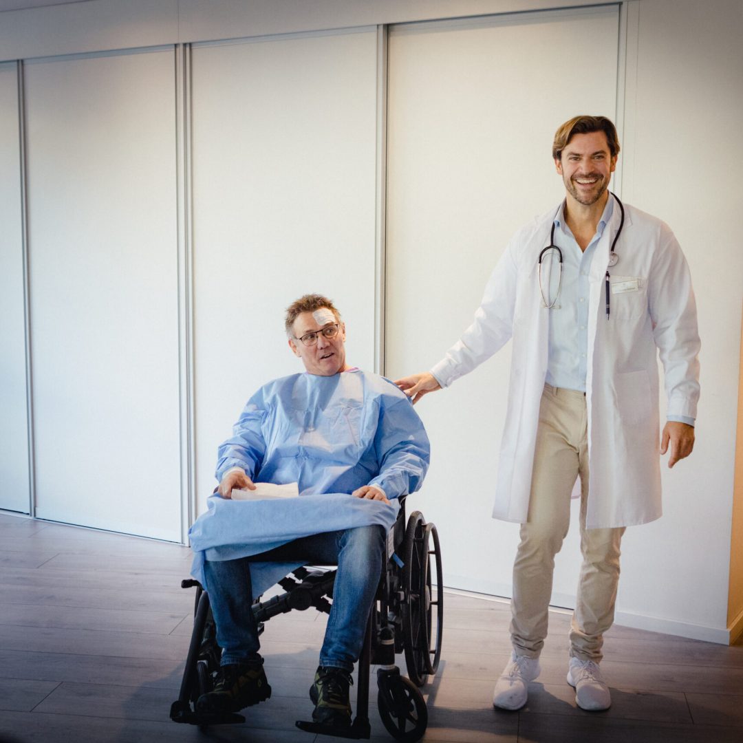 Behind the Scenes of two actors in, one a doctor and one a patient.